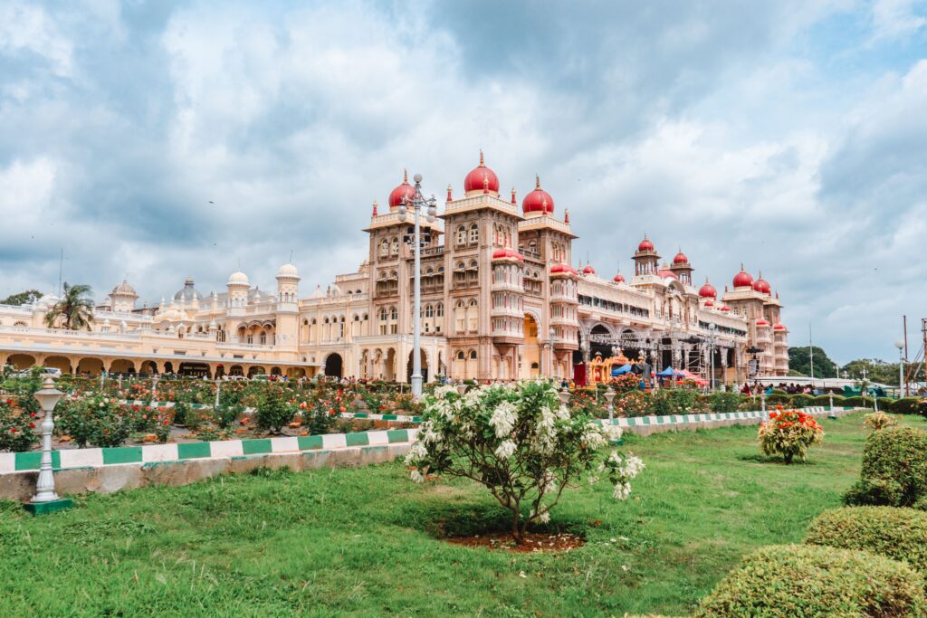 Stunning view of Mysore Palace in Karnataka, showcasing its ornate architecture and lush gardens under a cloudy sky.